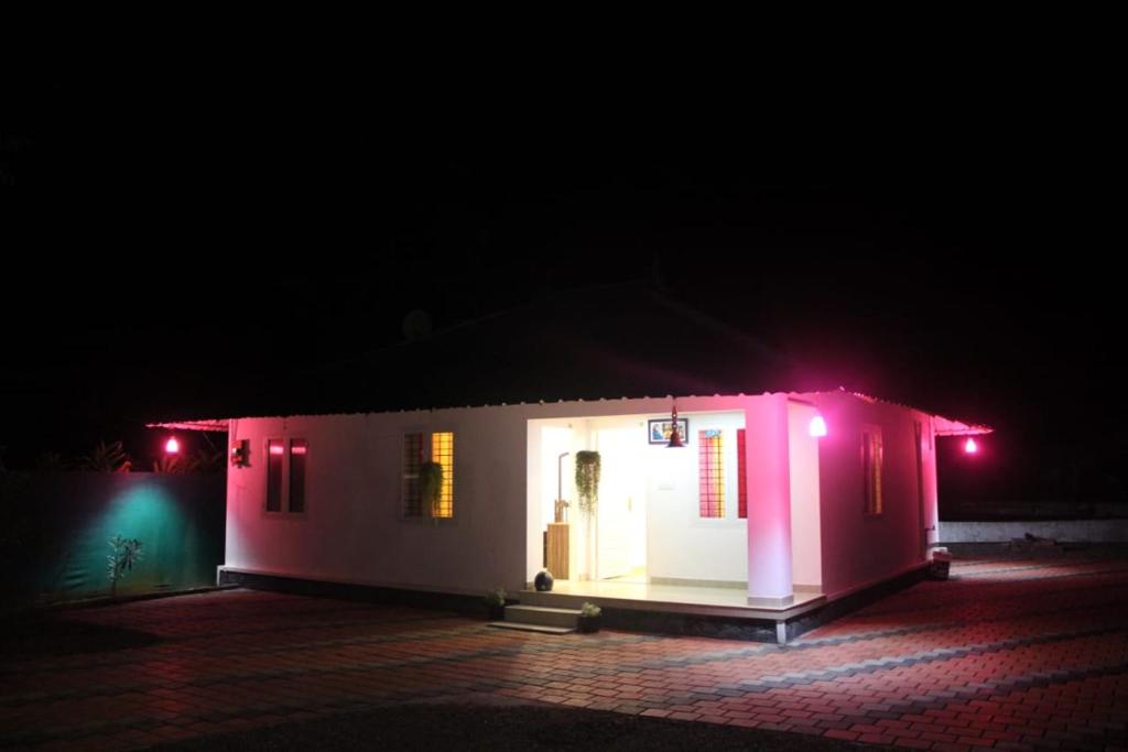 a small house with pink lights in the dark at Cassa Cottage Munnar in Kallar Vattiyar