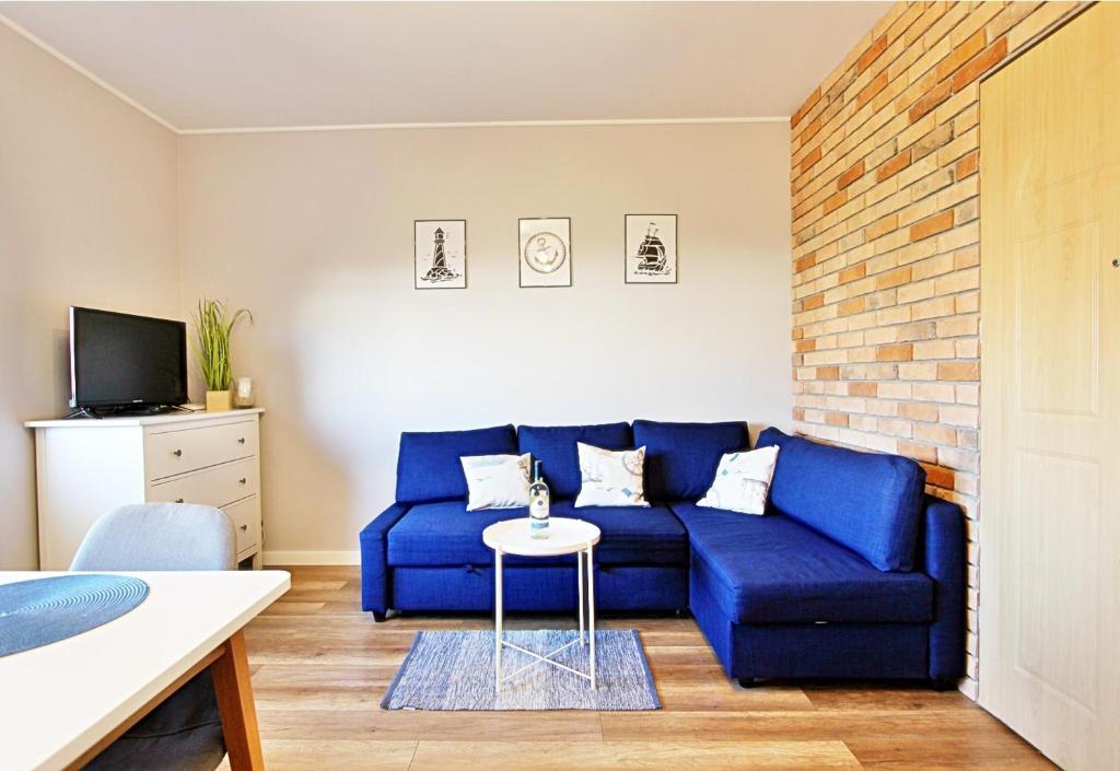 Sofá azul en la sala de estar con mesa en Apartament Kotwica z prywatnym miejscem w hali garażowej, en Świnoujście