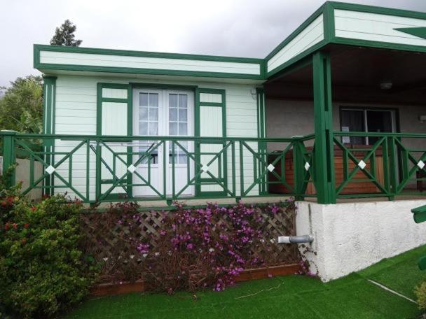 een groen en wit huis met een veranda en bloemen bij Loca Sun Résidence in Le Guillaume