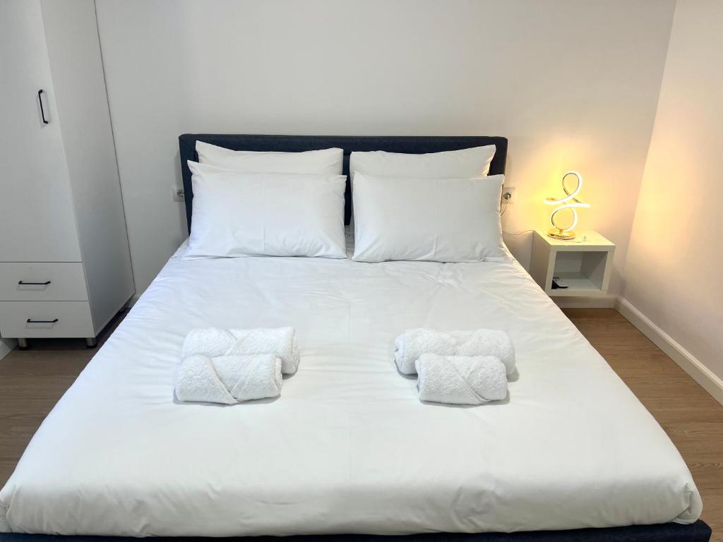 a large white bed with two towels on it at Viva Apartments in Përmet