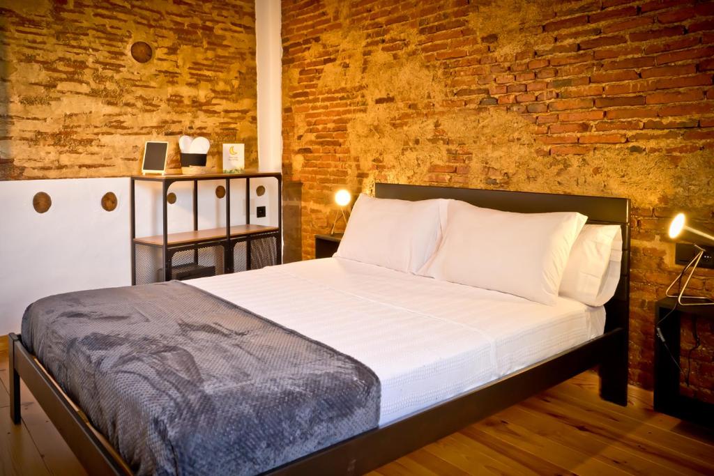 a bedroom with a bed and a brick wall at Hotel Casa Luna in Zafra