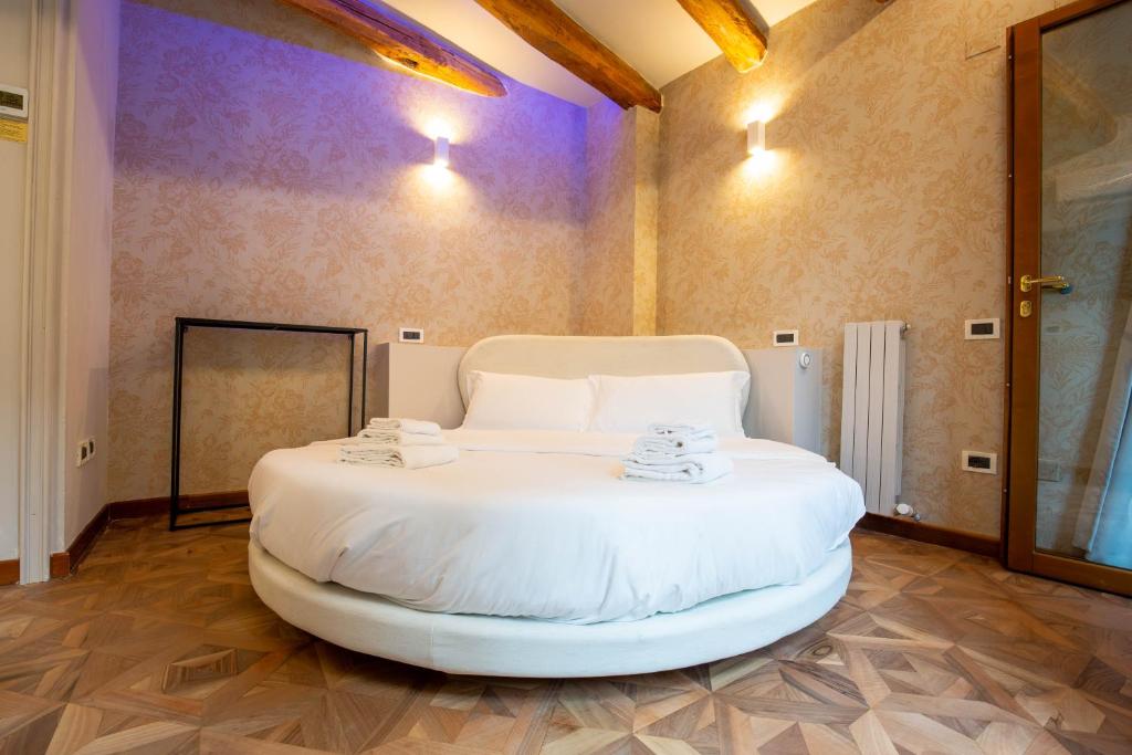 a large white bed in a room with wooden floors at BolognaRoomscom - Falegnami Boutique in Bologna