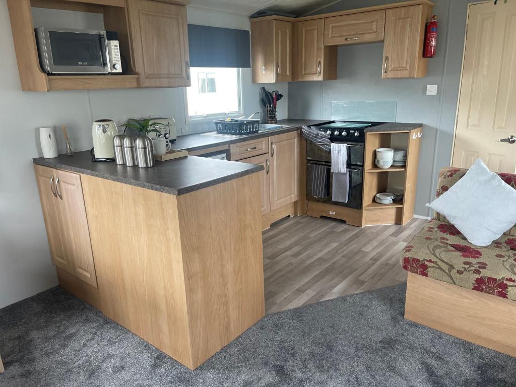 uma cozinha com armários de madeira e uma bancada em Amore Caravans em Porthcawl