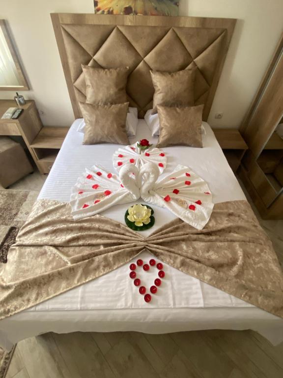 a bed with a white bedspread with red flowers on it at Apartments Gusar in Ulcinj