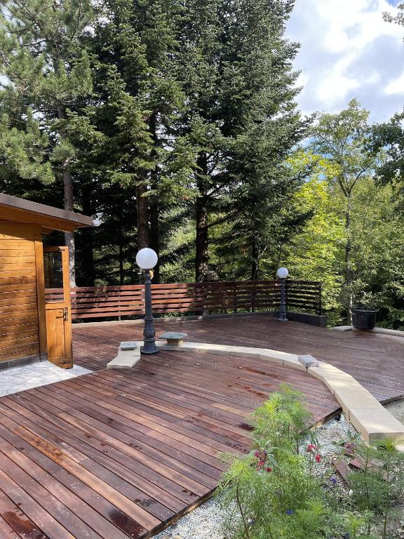 a wooden deck with benches and a fence and trees at Chalet Leonard House in the wood in Pennabilli
