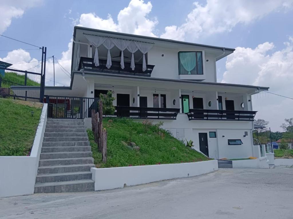 une maison blanche avec des escaliers en face de celle-ci dans l'établissement I Do Farmstay, à Bukit Mertajam