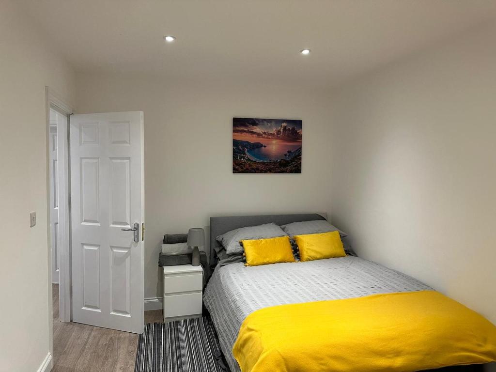 een slaapkamer met een bed met gele lakens en een deur bij 2 bedroom apartment in Londen