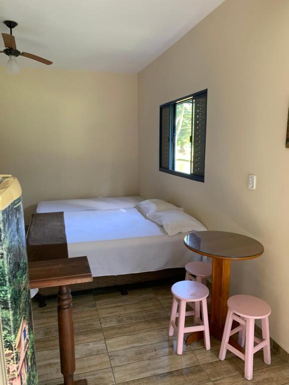a bedroom with a bed and two stools and a table at Fazenda Camping Cabral in São Lourenço