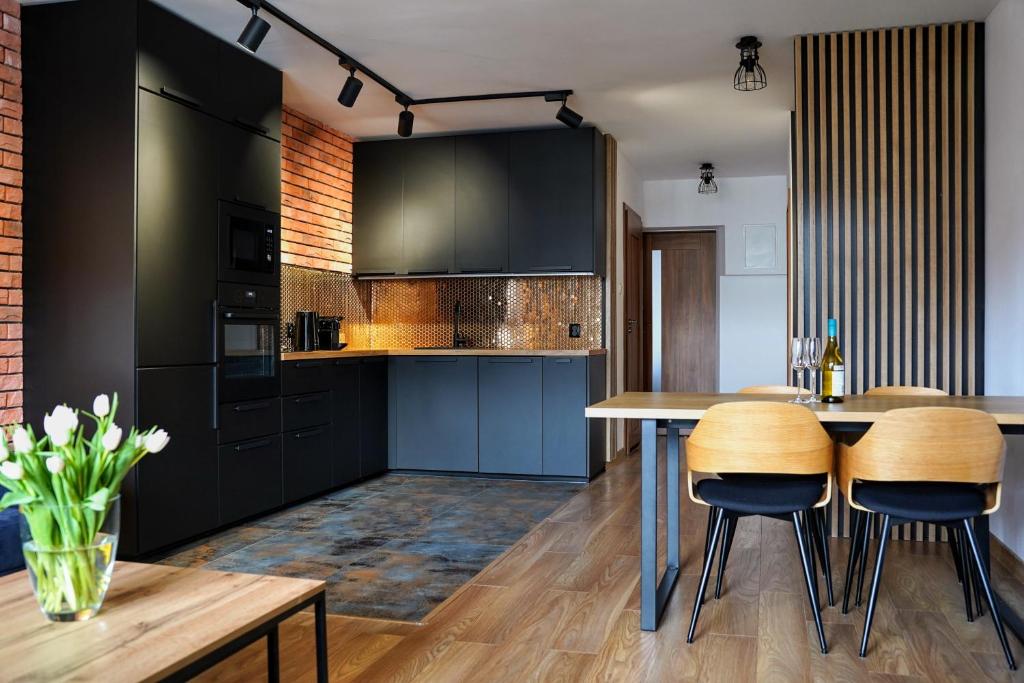 una cocina con armarios negros y mesas y sillas de madera en Apartament 914, en Wisła