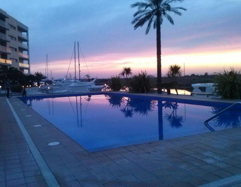 una gran piscina con palmeras y barcos en Atico en Port gran Roses, en Roses