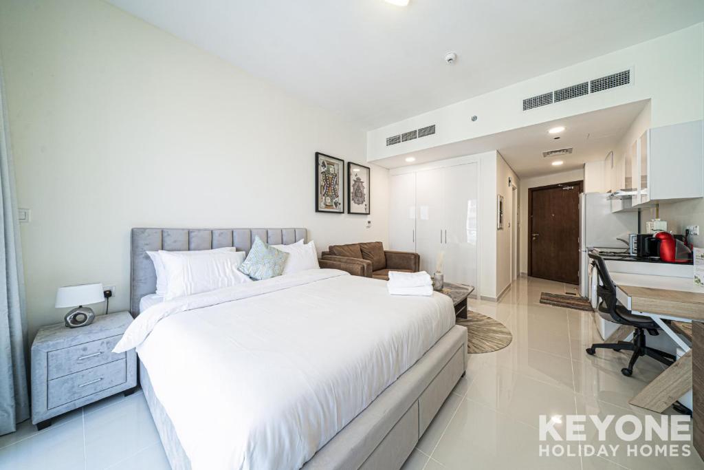 a bedroom with a large white bed and a desk at Modish Studio in Damac Hills 2 in Dubai