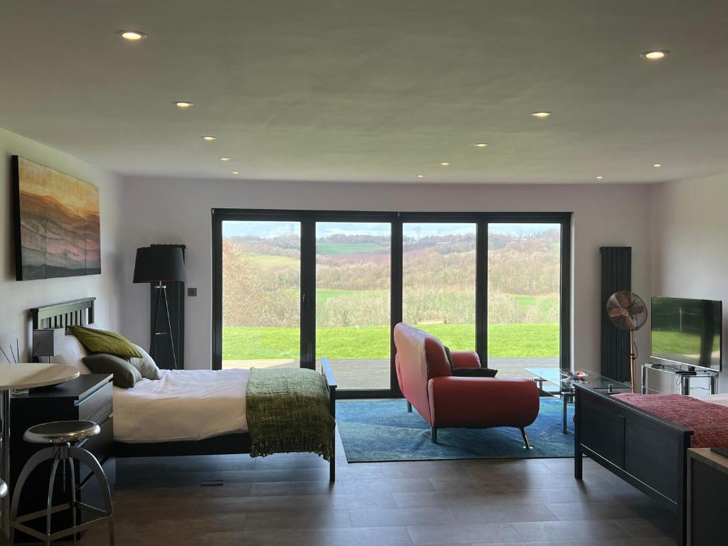 a bedroom with a bed and a couch and a chair at The Pod in Crowhurst