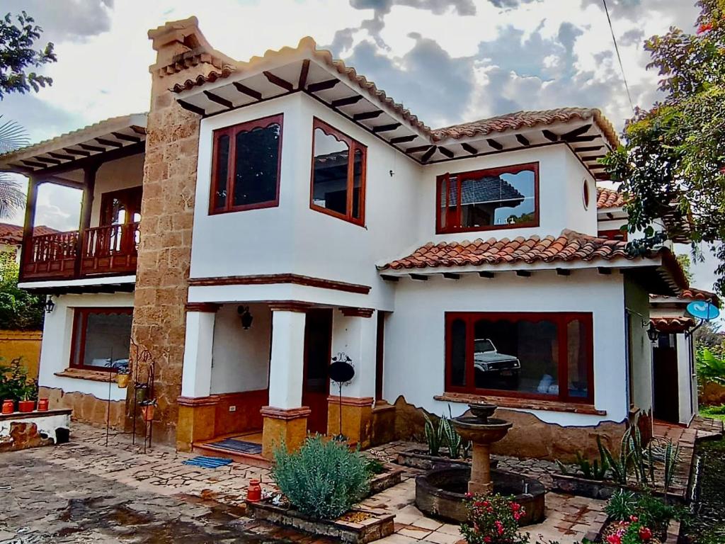 a white house with red windows in a yard at CASONA DE LOS VIRREYES in Villa de Leyva