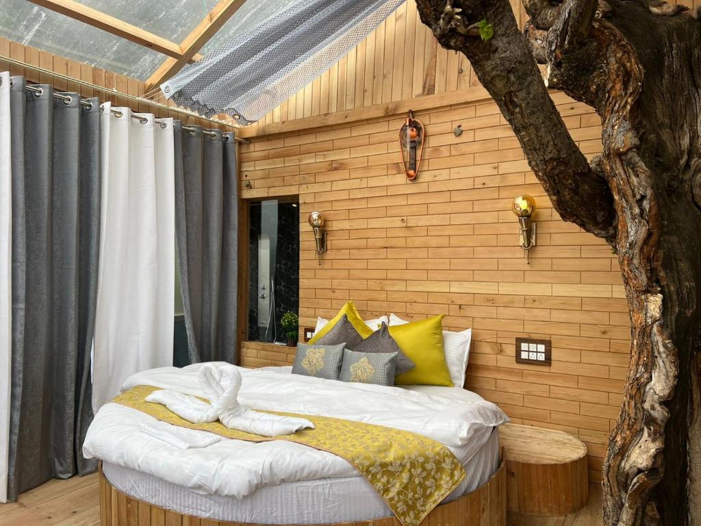 ein Schlafzimmer mit einem großen Bett mit gelben Kissen in der Unterkunft Cloudwalk Treehouse in Jibhi