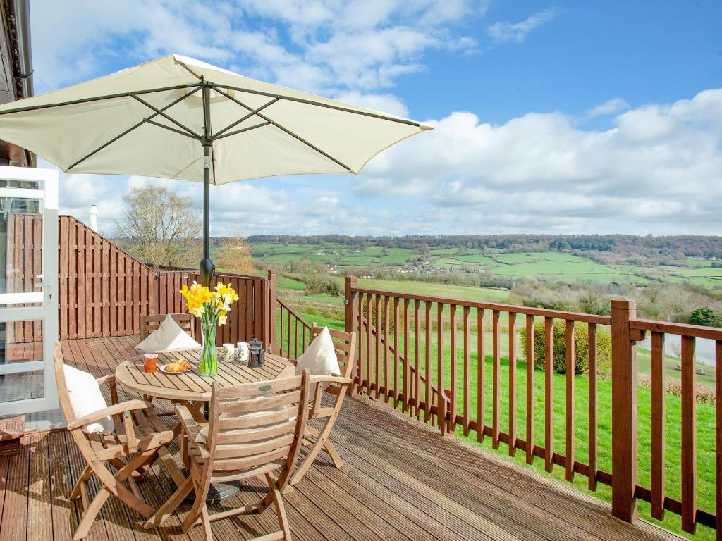 a wooden deck with a table and an umbrella at Valley View - Uk43268 in Luppitt