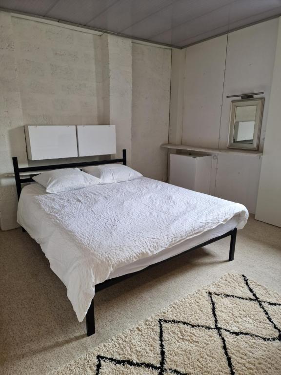 ein Schlafzimmer mit einem großen Bett mit weißer Bettwäsche und einem Teppich in der Unterkunft LES CERISIERS 2 in Nogaro