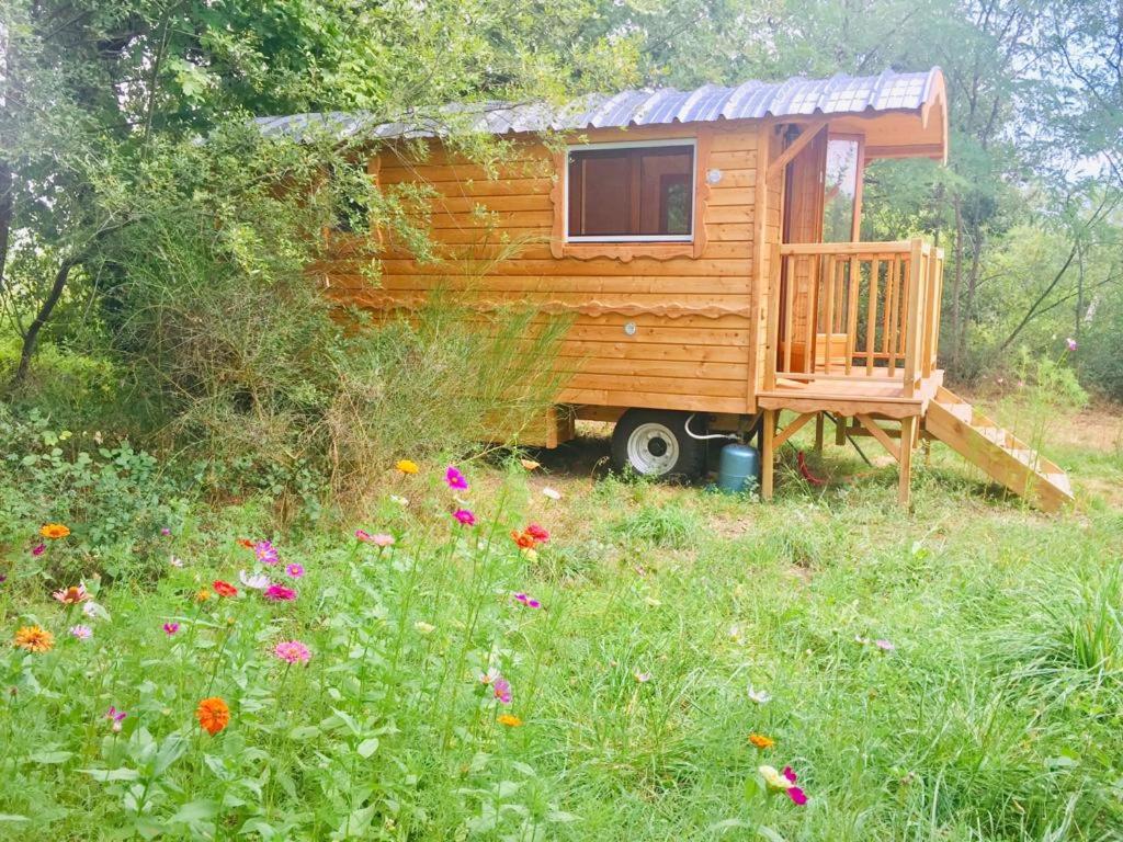 Une petite maison en bois dans un champ de fleurs dans l'établissement Roulotte Un temps pour soi, à Bérat