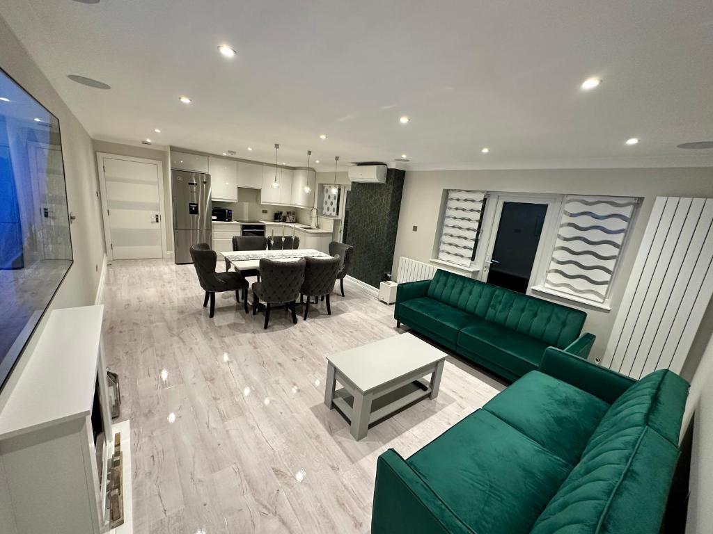 ein Wohnzimmer mit einem grünen Sofa und einem Tisch in der Unterkunft Luxury House in Greenford