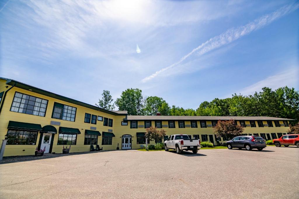 a yellow building with cars parked in a parking lot at The Lodge at Poland Spring Resort in Poland Spring