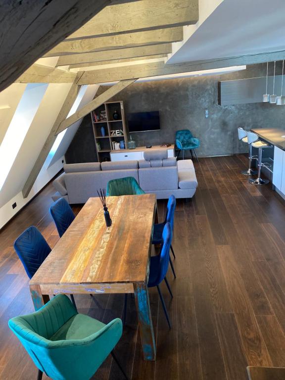 a living room with a wooden table and blue chairs at La Mezzanine des Rohan Saverne in Saverne