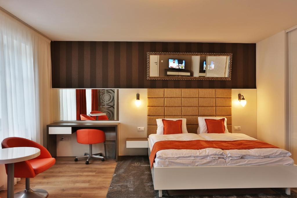 a hotel room with a bed, desk, chair and a lamp at VIP Apartments in Bratislava
