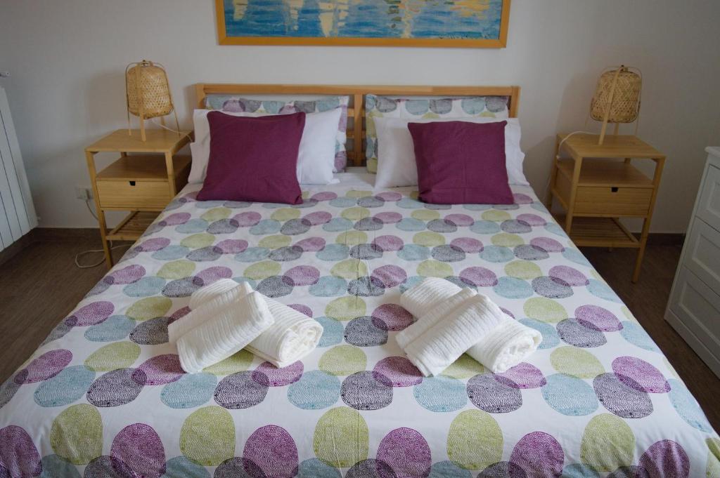 a bedroom with a large bed with purple and purple pillows at Peppe's house in Gravina di Catania