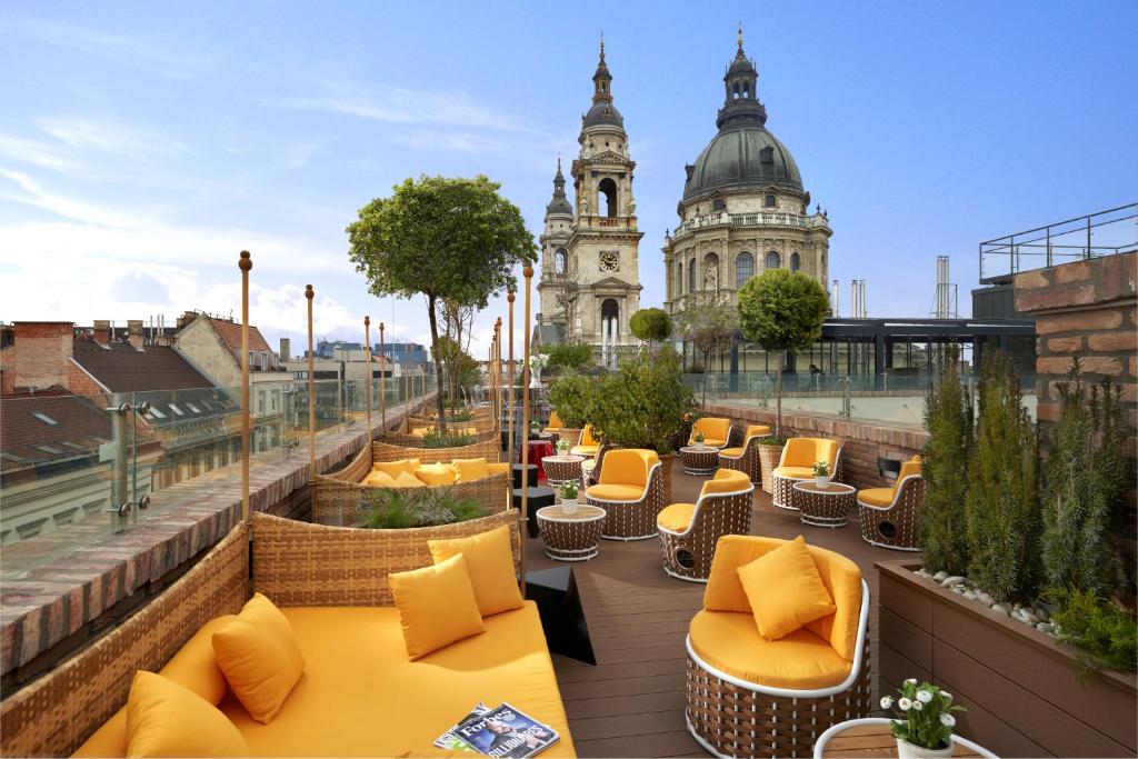 a rooftop patio with yellow chairs and a building at Aria Hotel Budapest by Library Hotel Collection in Budapest