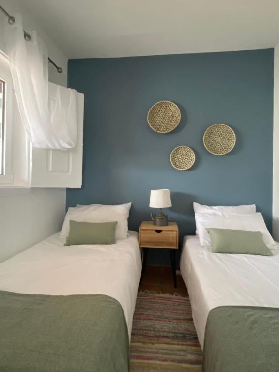 two beds in a room with a blue wall at A Quinta da Estrelinha in Quinta de Cavaleiros