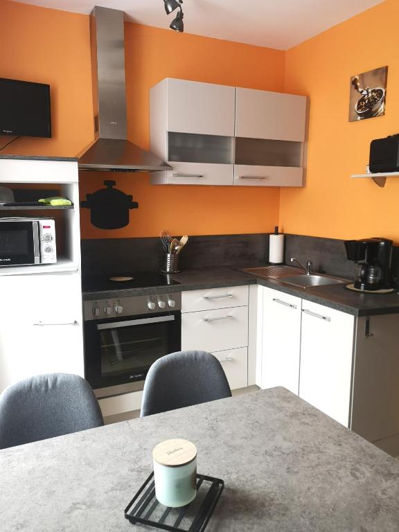 une cuisine avec des armoires blanches et une table avec des chaises dans l'établissement Appartement idéalement situé, à Le Mont-Dore