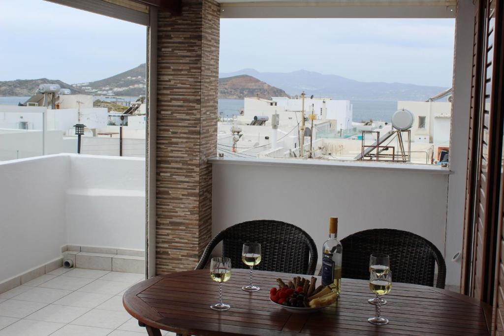 una mesa de madera con copas de vino en el balcón en Kapetanos Rooms, en Naxos Chora