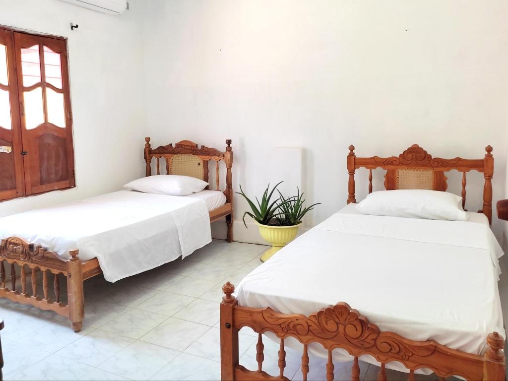2 camas en una habitación con paredes blancas en Hostal Casa La Candelaria, en Mompós