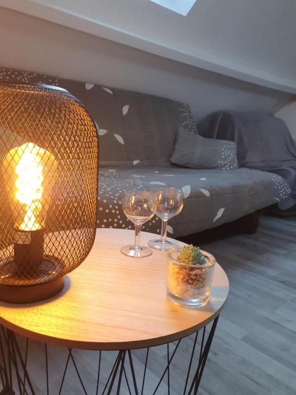a table with two wine glasses and a couch at Gites Des Petits Près in Fatouville-Grestain