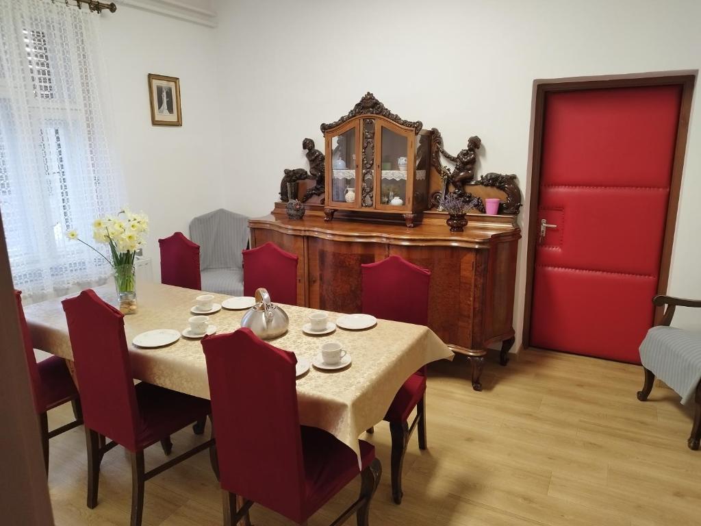 een eetkamer met een tafel met stoelen en een rode deur bij Tartós Szegfű Vendégház, Magánszállás in Tázlár