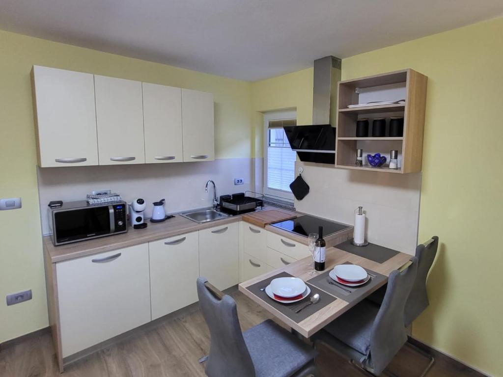 uma cozinha com armários brancos e uma mesa com cadeiras em Apartma Melita em Kobarid