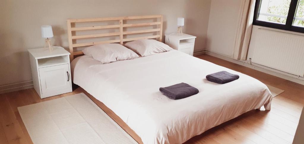 a bedroom with a large white bed with two towels on it at Les 3 Mésanges in Giverny