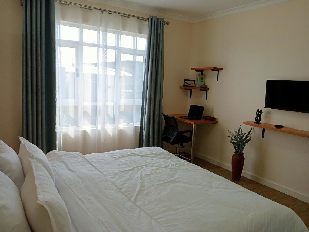 a bedroom with a white bed and a window at Luxury Cosy Homestay with Private Entrance in Eldoret