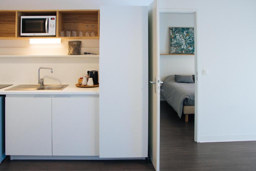 a kitchen with white cabinets and a sink and a bed at Twenty Business Flats Le Mans Ouest in Le Mans