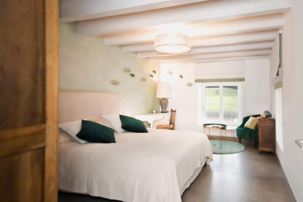 a bedroom with a large white bed with green pillows at Les Champs du Levant in Cudrefin