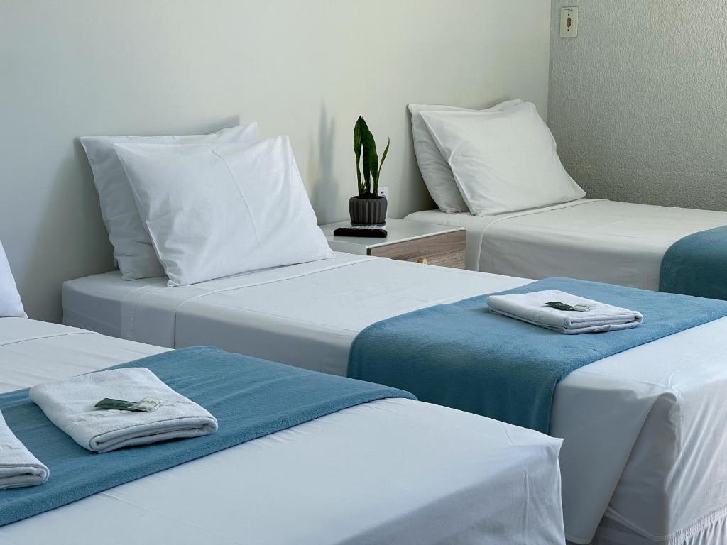 three beds in a room with towels on them at Hotel Dallas in Penha