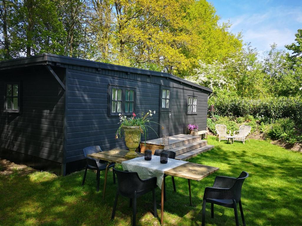 een zwarte schuur met een tafel en stoelen in een tuin bij Het Nijhuisje in Markelo