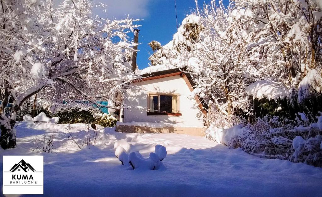 a house covered in snow in front of trees at Cabaña Kuma Bariloche Barrio Melipal in San Carlos de Bariloche
