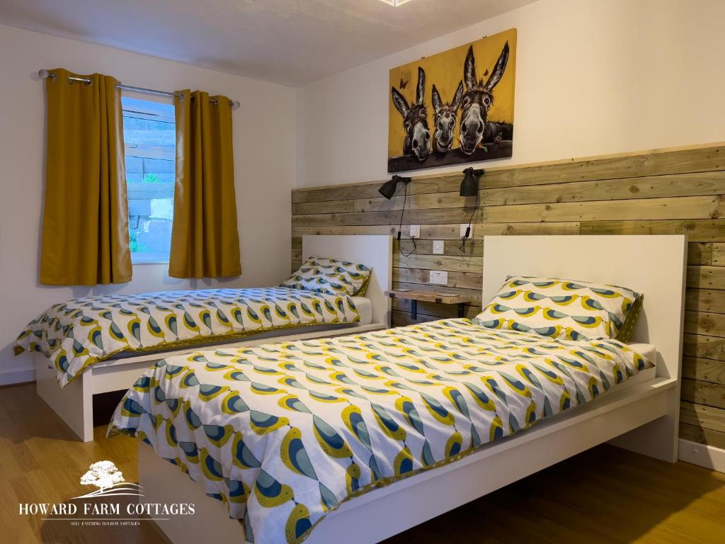 sypialnia z 2 łóżkami i drewnianą ścianą w obiekcie Howard Farm Holiday Cottages w mieście Bude