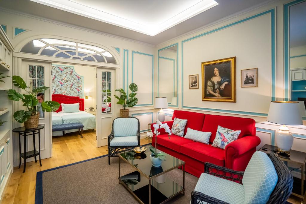 uma sala de estar com um sofá vermelho e uma cama em Grande Hotel do Porto no Porto