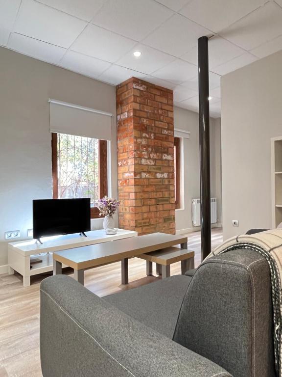 uma sala de estar com uma mesa e uma parede de tijolos em CASA BASELGA Apartamento em Barbastro