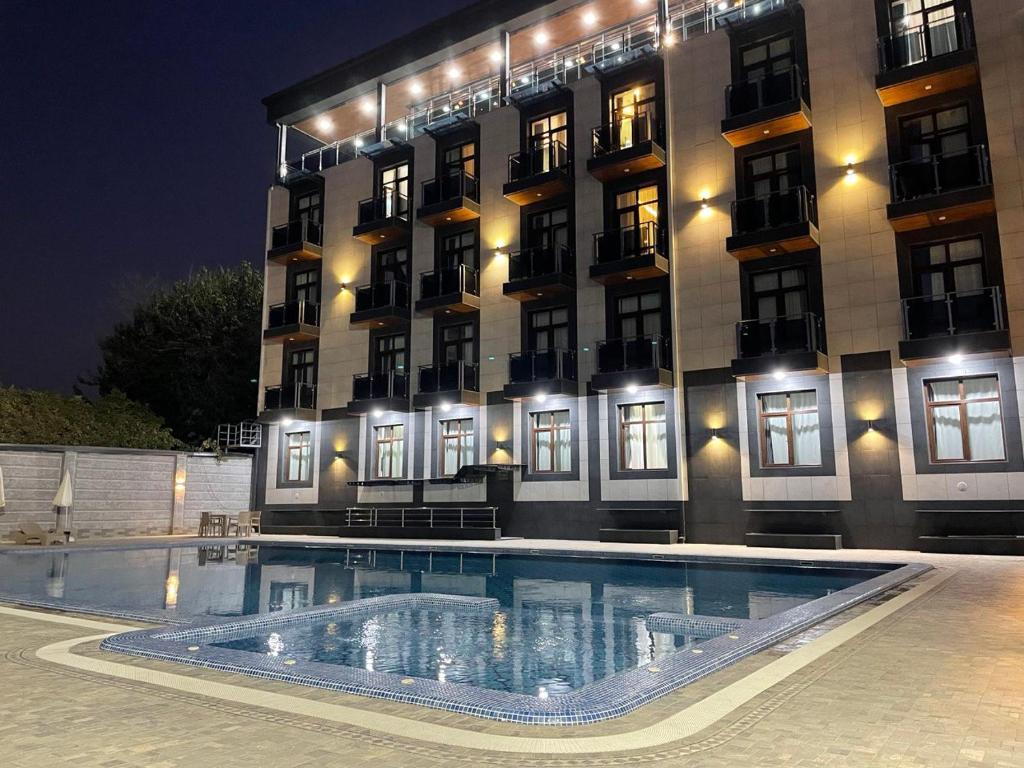 a hotel with a swimming pool in front of a building at Rayyan Hotel & SPA Tashkent in Tashkent