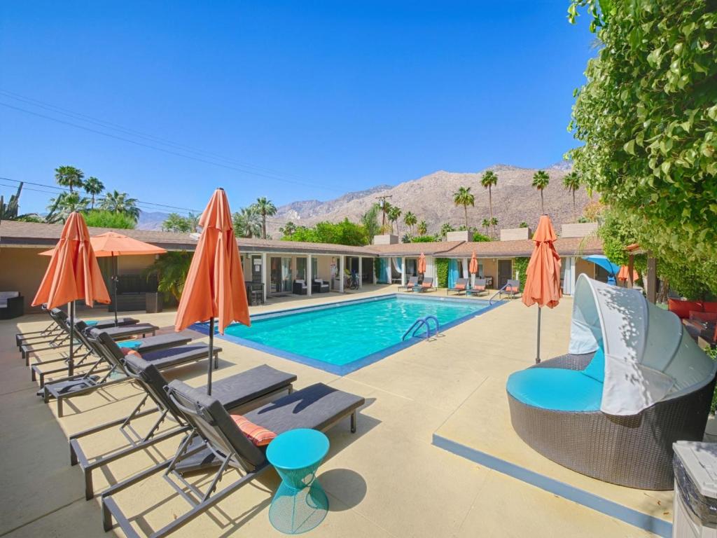 a swimming pool with lounge chairs and umbrellas at Little Paradise Hotel in Palm Springs