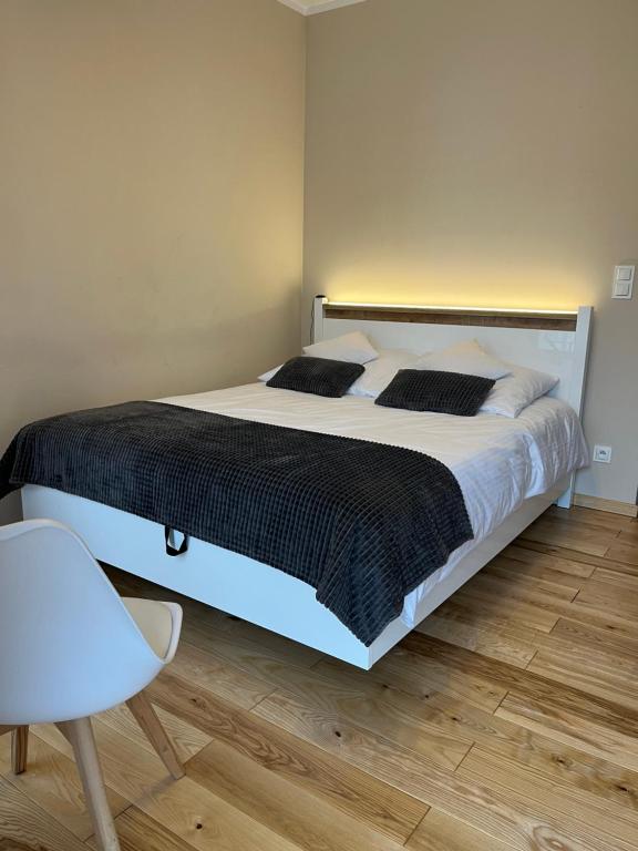 a bedroom with a large bed and a chair at Apartament Garbary 84 in Poznań