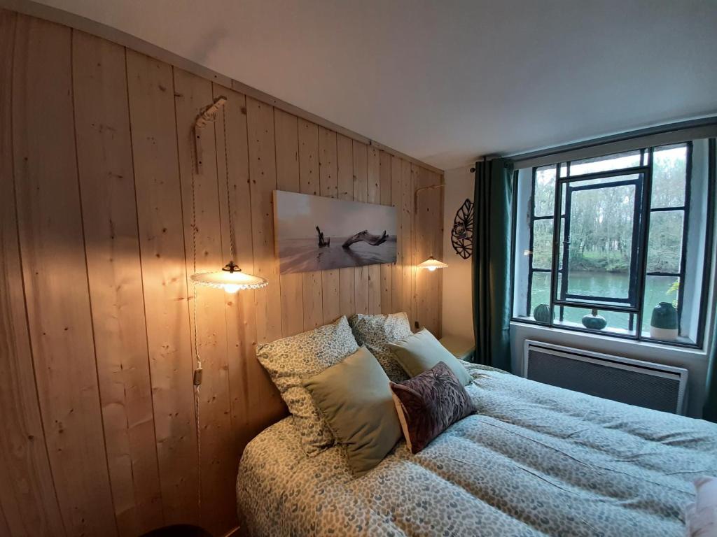 1 dormitorio con cama y ventana en Dans moulin au bord de l'eau, Appartement chaleureux en Saint-Pryvé-Saint-Mesmin