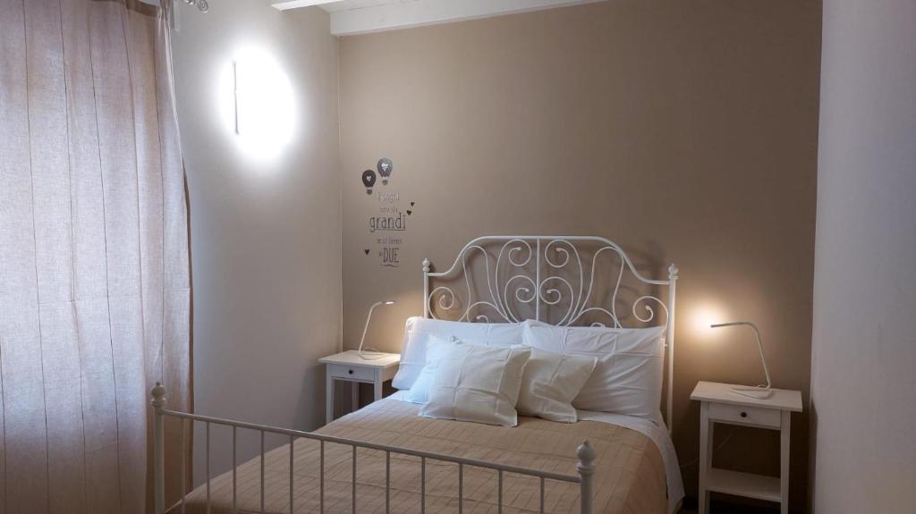 a bedroom with a bed with white pillows and lamps at Casa Monchieri in Marone