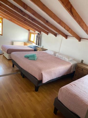 um quarto com três camas num quarto em Nikos II Adventure em Puerto Natales